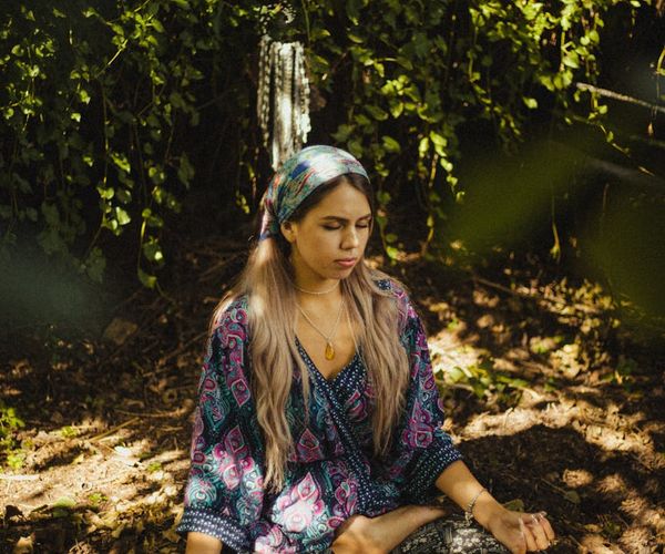 Person sitting in a lotus pose meditating in a quiet, sunlit room.